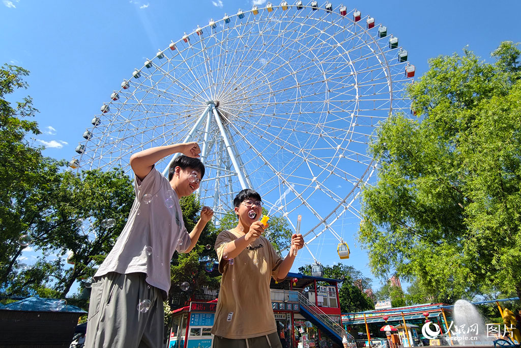 2026年5月30日，在遼寧沈陽萬泉公園，孩子們正在88米高的摩天輪下快樂地玩耍。人民網(wǎng)記者 周頌雪攝